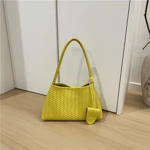 Close-up of yellow woven leather shoulder bag showing intricate intrecciato details.