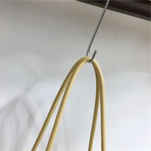 Detailed close-up view of the yellow soft leather woven handbag handle hanging on a metal hook.