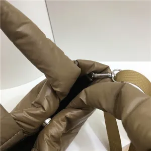 Gros plan sur les détails de la sangle et la texture en métal de la pochette matelassée.