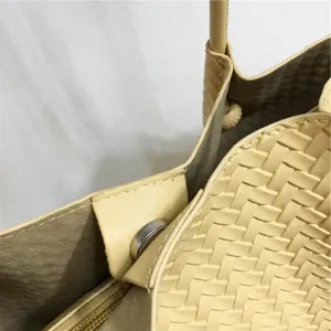 Close-up of soft woven leather handbag showing detailed intrecciato weave and snap.