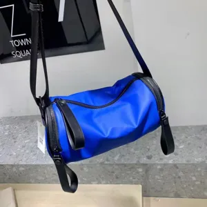 Blue nylon barrel shoulder bag detail, waterproof crossbody bag with dual zippers.