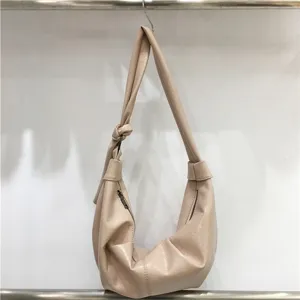 Detailed shot of beige soft leather pleated shoulder bag, slouchy hobo dumpling design.