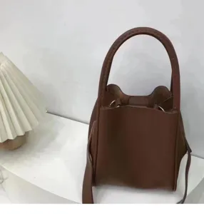 Brown leather bucket handbag detail view, showing texture and handle design for daily wear.