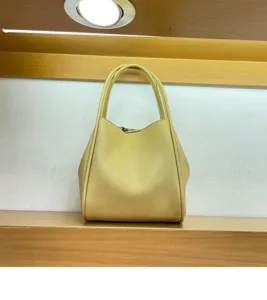 Detail view of the yellow leather bucket bag handle and grain texture closeup display.