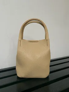 Vista dettagliata di una mini borsa a secchiello in pelle beige, elegante e compatta per l'uso.