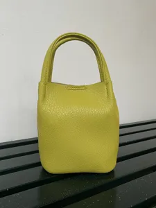 Scatto dettagliato di una borsa a secchiello in pelle chartreuse con due manici e cuciture.