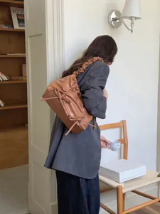 Gedetailleerd overzicht van bruine gefronsde schoudertas met strikaccenten voor dagelijks gebruik.