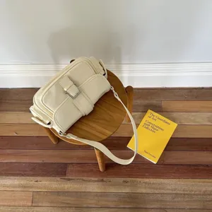 Detailed view of the stylish off-white shoulder bag showcasing its unique multi-pocket design.