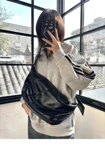Detailed view of the black oil-waxed leather crescent shoulder bag with wide strap.