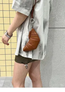 Detailed view of the brown soft leather croissant coin purse hanging from a stylish ring strap.