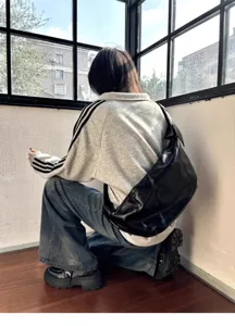 Detailed view of black oil-wax leather hobo shoulder bag in indoor window scene style.