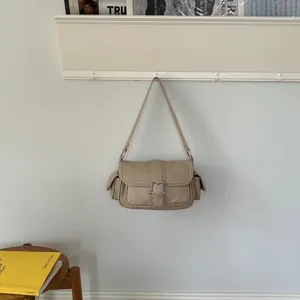 Detailed view of trendy beige utility shoulder bag with side pockets and front buckle accent.