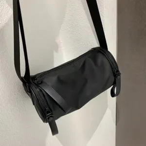 Black nylon cylindrical crossbody bag, minimalist shoulder handbag for daily wear.