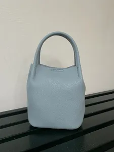 Vista dettagliata di una mini borsa a secchiello in pelle azzurra con finitura strutturata.