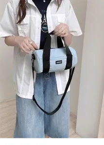 Detailed view of the light blue cylindrical canvas shoulder bag with black webbing straps.