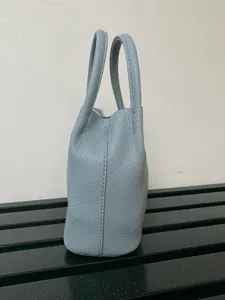 Mini borsa a secchiello in pelle azzurro chiaro, design classico con manico per uso quotidiano.