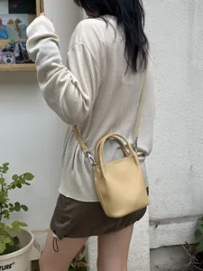 Vista dettagliata della borsa a secchiello mini gialla da donna, accessorio moda.