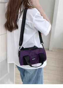 Detail view of stylish casual purple cylindrical canvas shoulder bag with black straps.