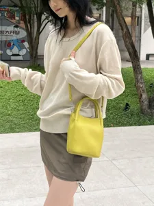 Vista dettagliata di una borsa a secchiello gialla da donna, trendy e compatta.