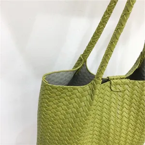 Green woven leather tote bag detail, featuring classic intrecciato style pattern and handles.