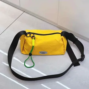 Detailed view of the yellow oxford cloth crossbody bag with black strap and green lanyard.