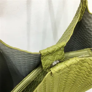 Green woven leather bag interior detail showing intrecciato texture and secure metal clasp.