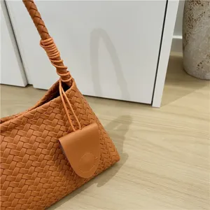 Woven leather shoulder bag detail, orange baguette bag style, chic minimalist design.