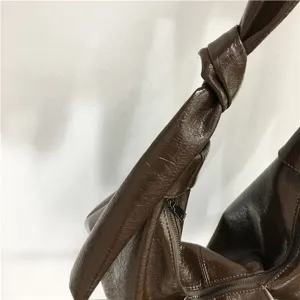 Close-up detail of the brown crinkled leather hobo bag showcasing the zipper and knotted strap design.