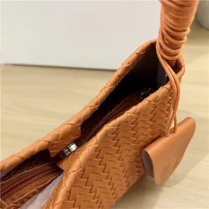 Close-up view of orange woven leather handbag detail, featuring intricate texture and hardware.