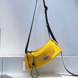 Detail view of bright yellow cylindrical crossbody bag showing texture and black strap
