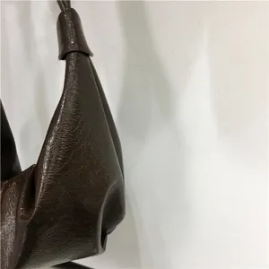Close-up detail of dark brown crinkled leather hobo bag, soft dumpling style texture.