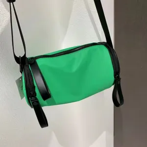 Detailed view of a vibrant green nylon crossbody barrel bag with black straps for daily use.