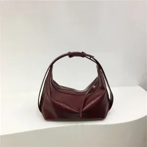 Detailed view of the minimalist burgundy dumpling hobo bag, showing smooth glossy PU leather.