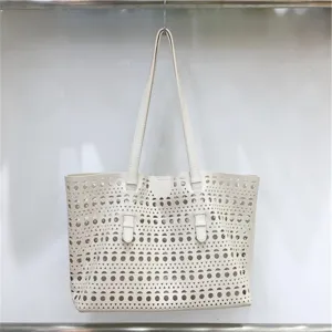 Close-up of the elegant white leather tote bag featuring intricate laser-cut perforated patterns.