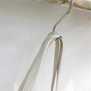 Close-up detail of luxury leather bag strap hanging on metal hook, premium craftsmanship.