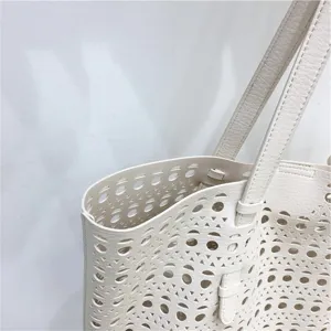 Close-up detail view of white leather laser cut perforated tote bag showing fine texture.