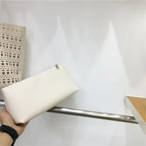 Detailed shot of minimalist white cosmetic clutch bag with elegant smooth texture for women.