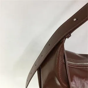 Brown glossy leather minimalist shoulder bag detail, soft dumpling crossbody bag for daily commute.
