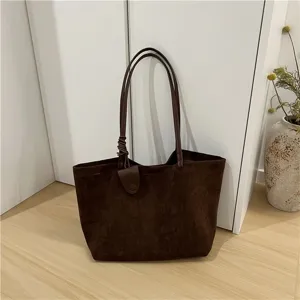Close-up detail of the brown faux suede tote bag showcasing its minimalist strap design and texture.