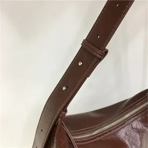 Detailed close-up view of the brown leather shoulder bag strap and metal zipper hardware.