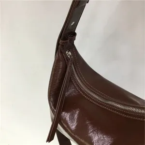 Brown patent leather shoulder bag detail, minimalist soft dumpling underarm handbag zipper.