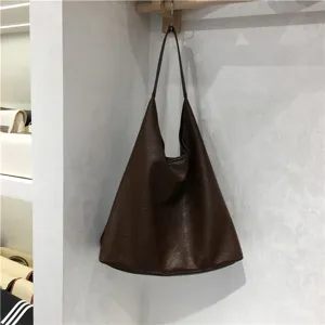 Detailed close-up showing the soft textured leather and slouchy shape of the brown tote bag.