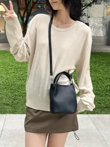 Dettaglio di una mini borsa a secchiello nera da donna, design a tracolla chic per l'estate.