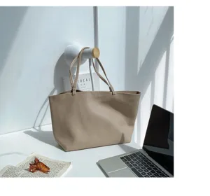 Casual beige soft leather tote bag showcased in a minimalist room interior setting detail.