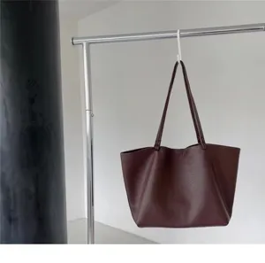 Dark red leather slouchy tote bag hanging on metal rack, detailed view of casual design style.