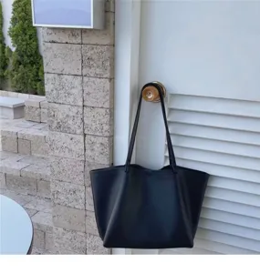 Close-up shot of a black slouchy leather tote bag hanging on a door handle, casual everyday style.
