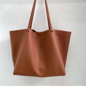 Detail view of brown slouchy leather tote bag showing soft texture and shoulder straps.