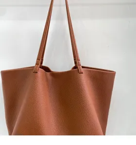 Close-up detail of soft brown leather slouchy tote bag showing fine texture and shoulder strap.