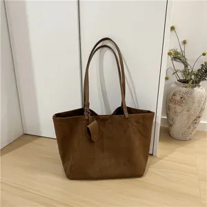 Details of brown suede tote bag, featuring soft fabric texture and dual straps for daily wear.