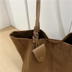 Close-up detail of brown suede tote bag strap and mini pouch accessory autumn style.